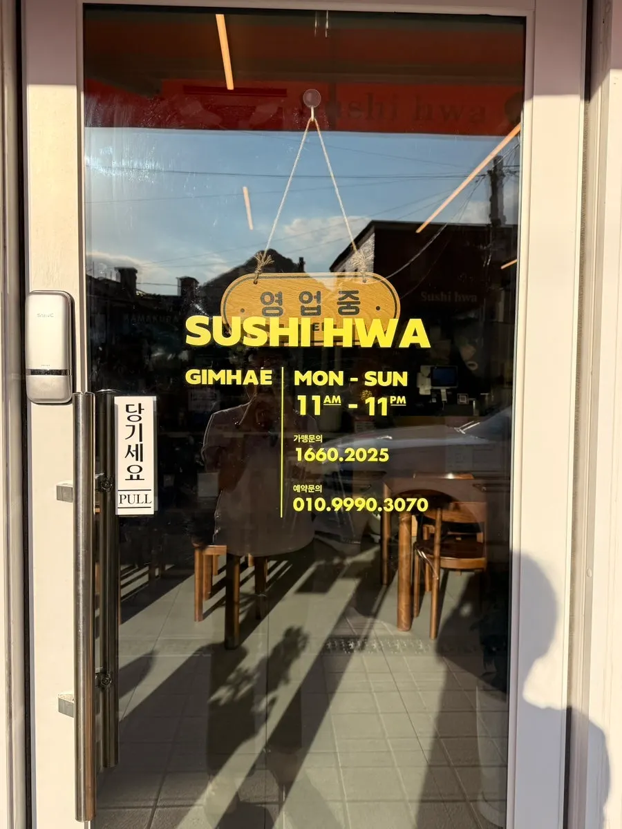 Sign showing Sushi Hwa's hours and safe restaurant designation