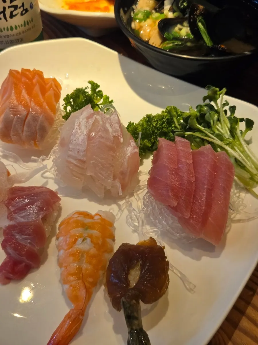 A plate of 12 pieces of flounder, salmon and tuna sashimi