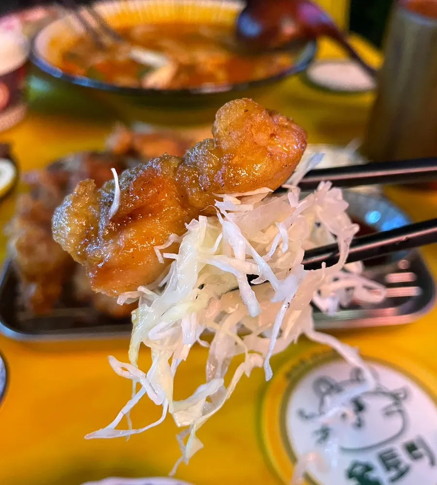 Chopsticks picking up a piece of black pepper karaage