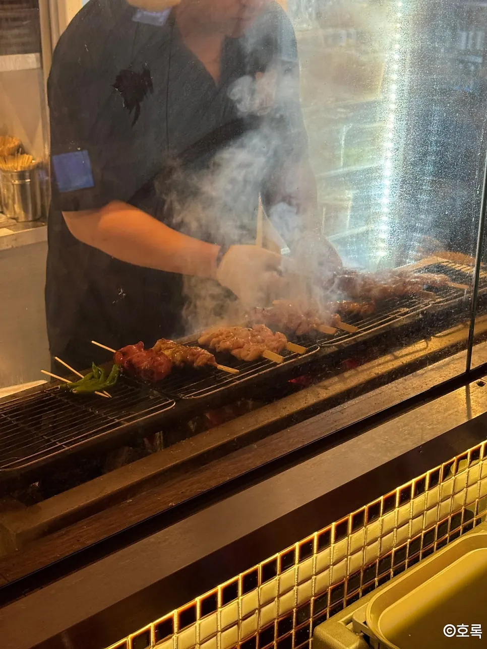 숯불 앞에서 꼬치를 굽는 주방 모습
