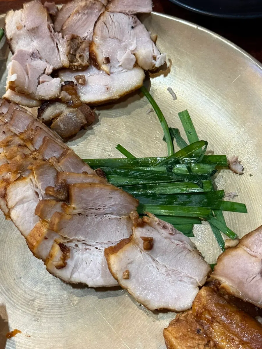 A perilla leaf wrap with meat, sliced garlic, and salted shrimp
