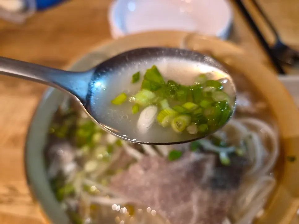 Pho noodles and brisket lifted up with chopsticks