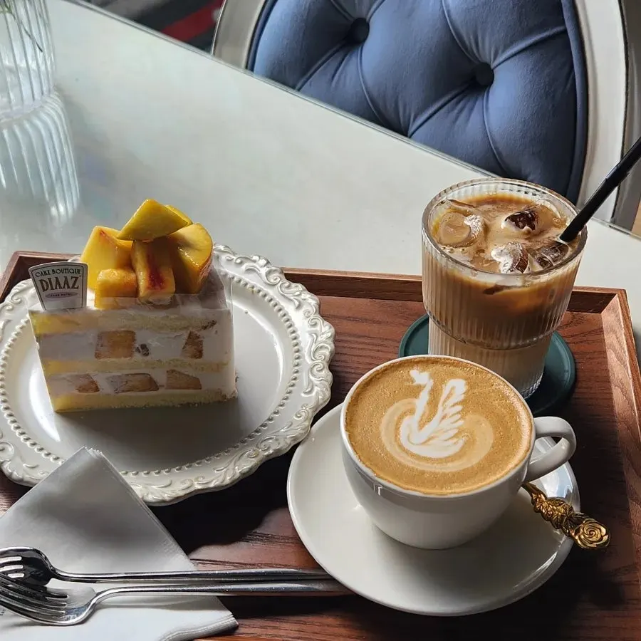 Cake and two cups of coffee at a sunlit window seat