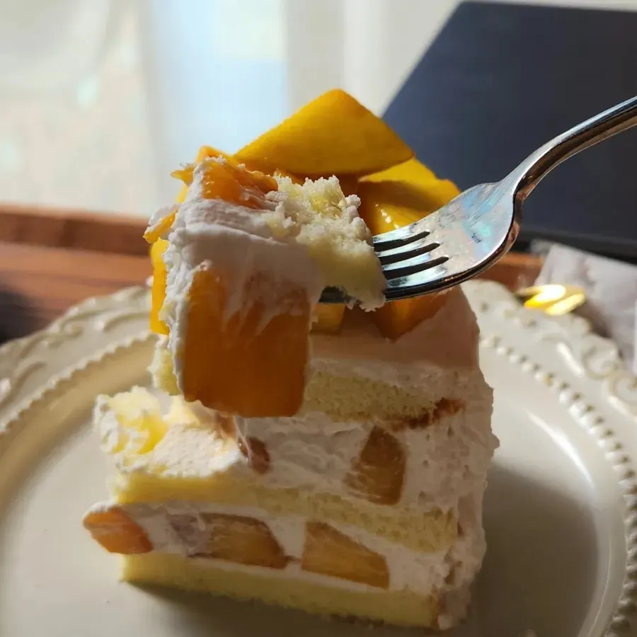Cross-section of peach fresh cream cake full of white peach