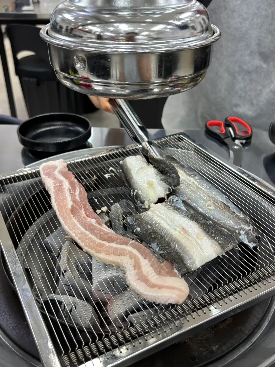 Eel and pork belly slowly cooking on the grill