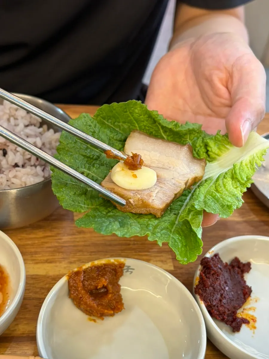 Dombe pork served with leafy greens and sauce