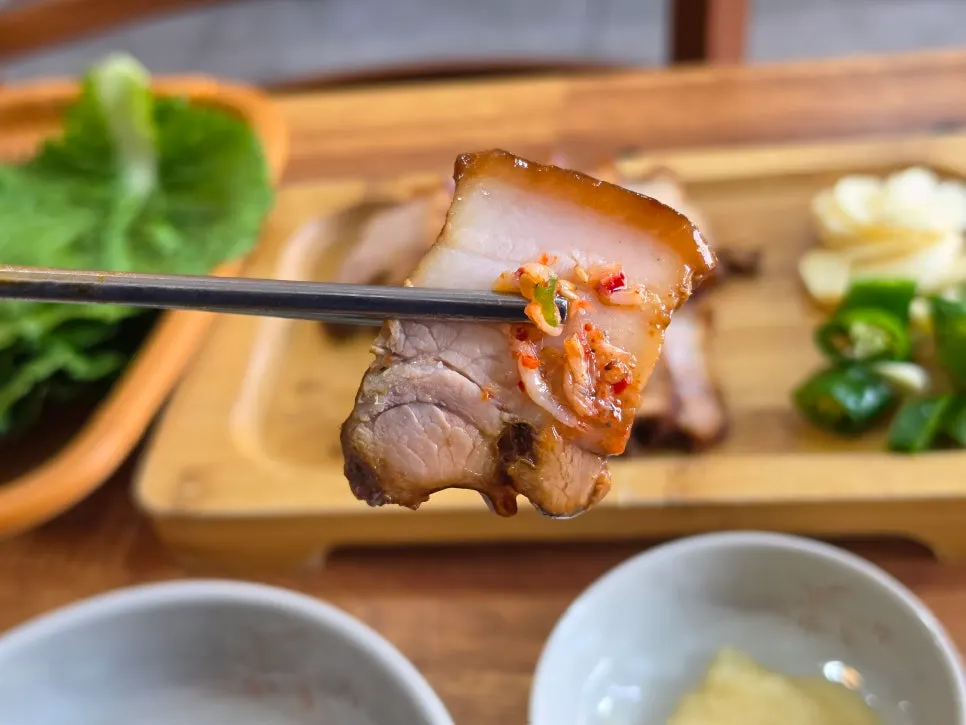 A piece of dombe pork picked up with chopsticks