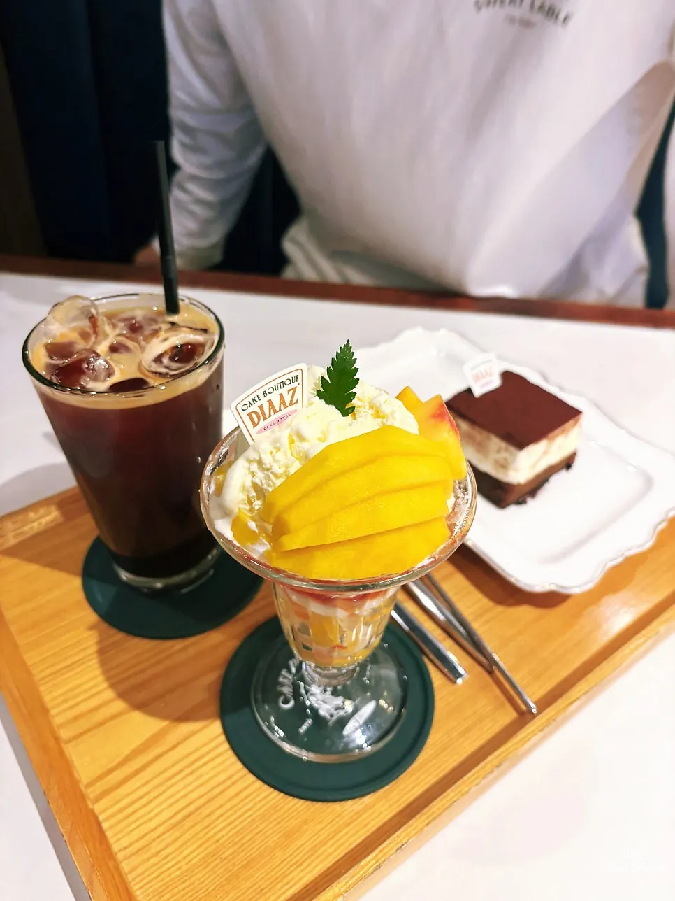 Table set with peach parfait, tiramisu, and iced americano