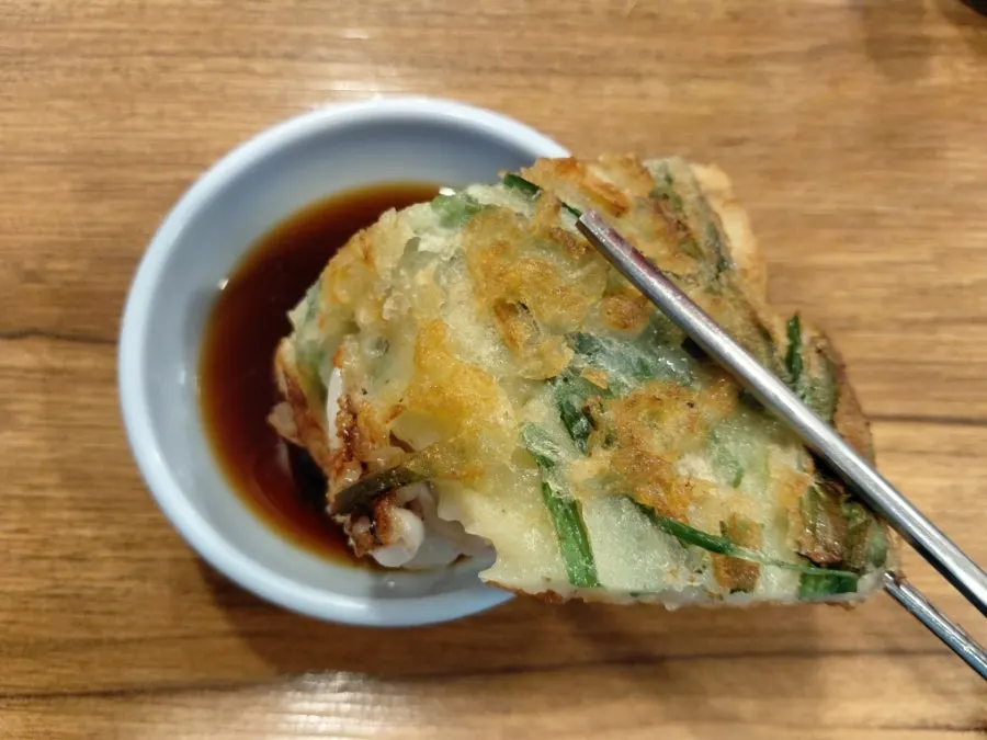 A piece of seafood pancake dipped in soy sauce