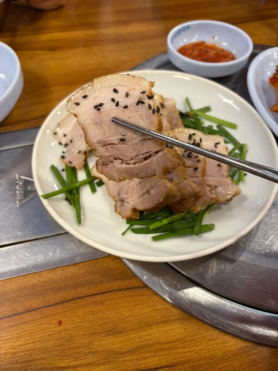 A bite of bossam topped with kimchi