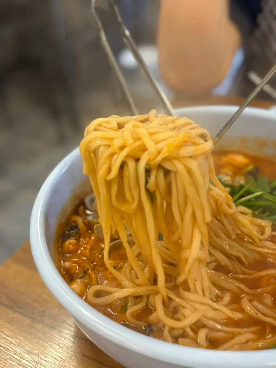 Chewy kalguksu noodles lifted with chopsticks