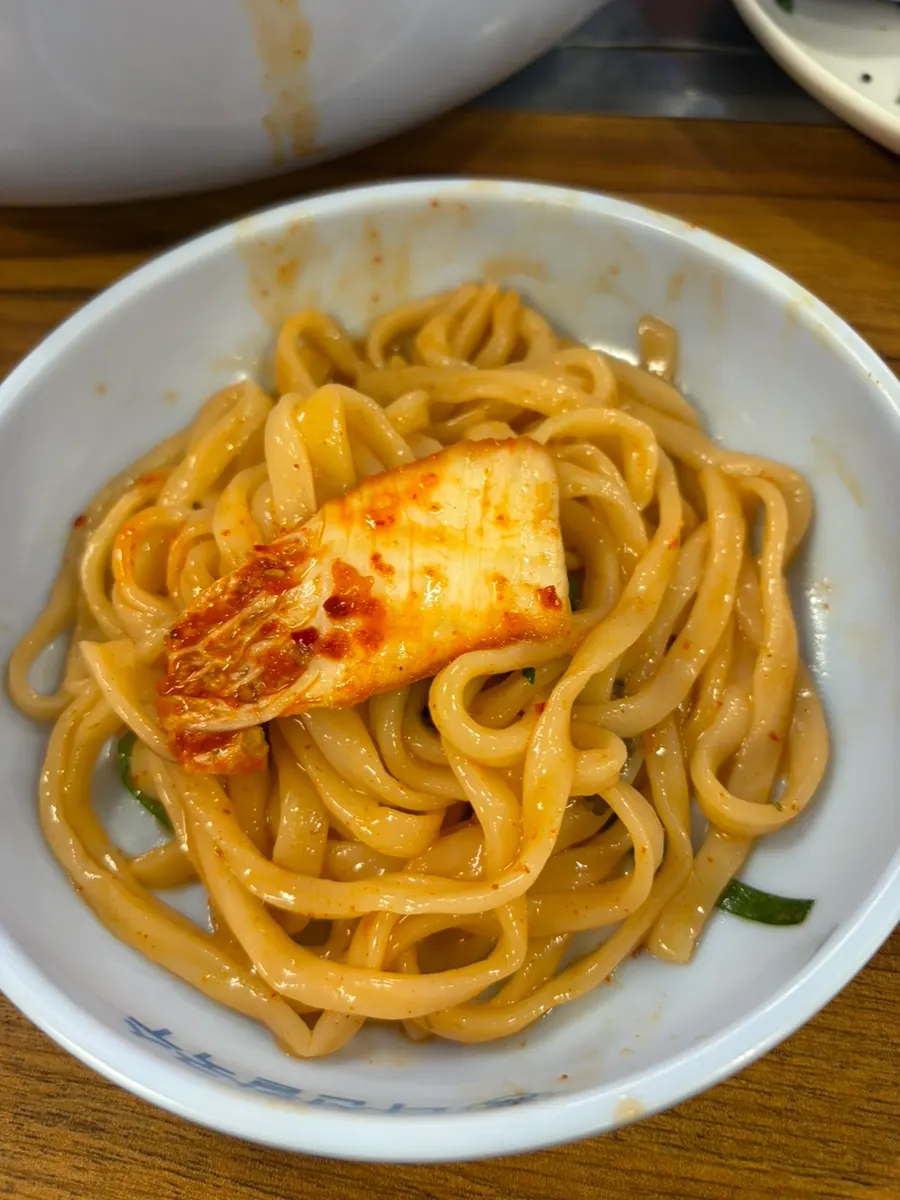 Kalguksu noodles topped with a piece of kimchi