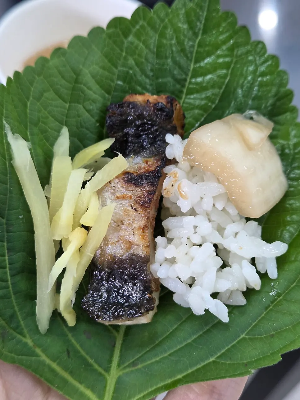 A piece of eel with shredded ginger and pickled onion