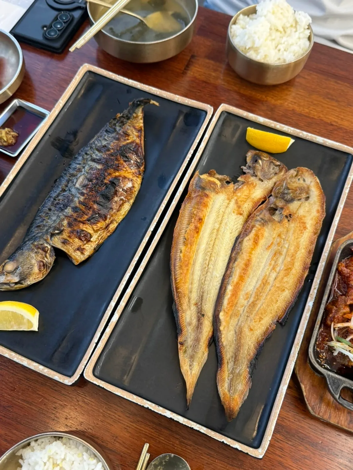 Full table spread of grilled fish and side dishes
