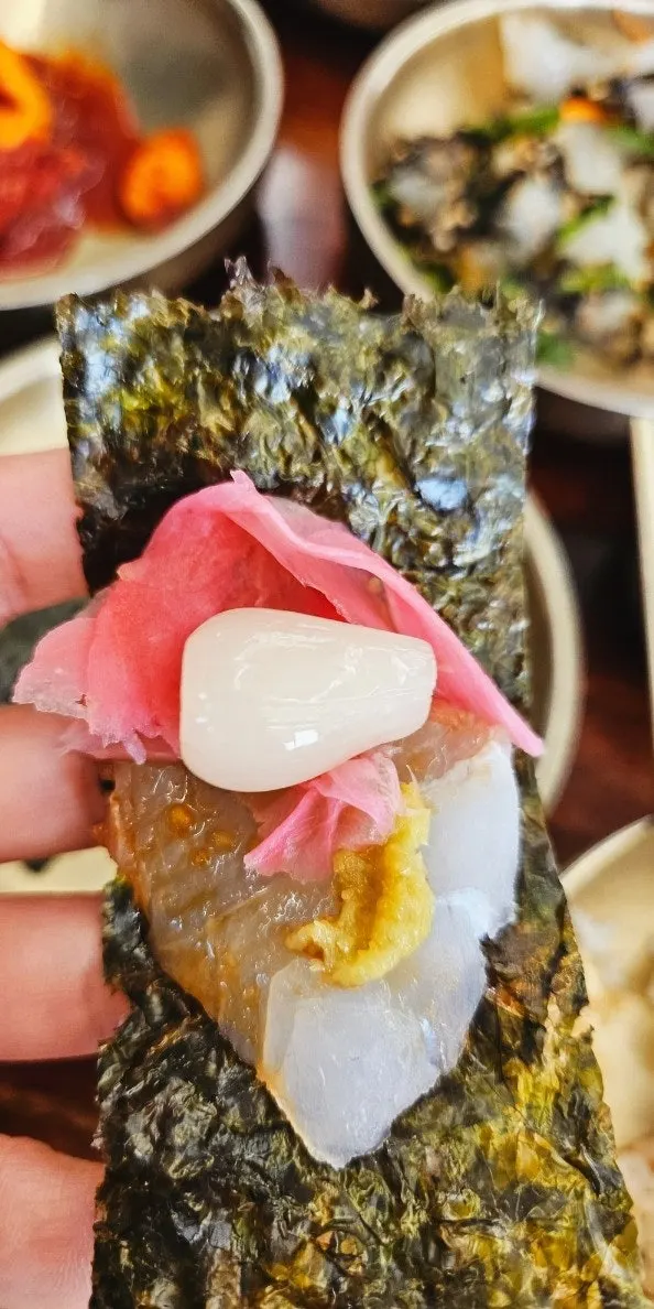 A bite of mackerel sashimi wrapped in seaweed