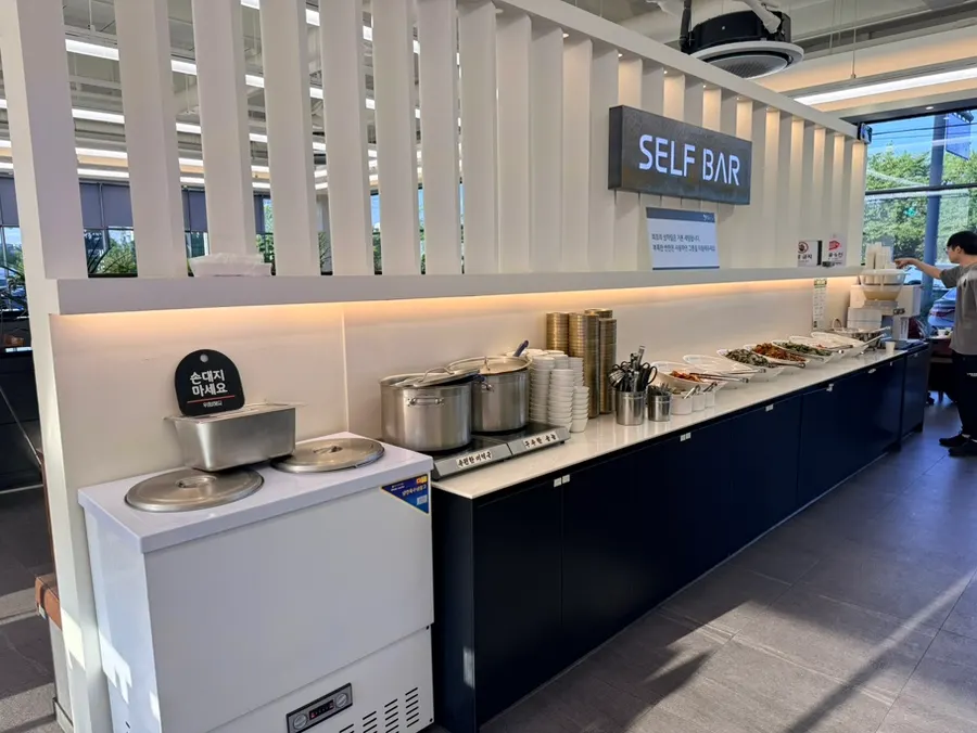 Self-bar lineup including japchae and fresh kimchi