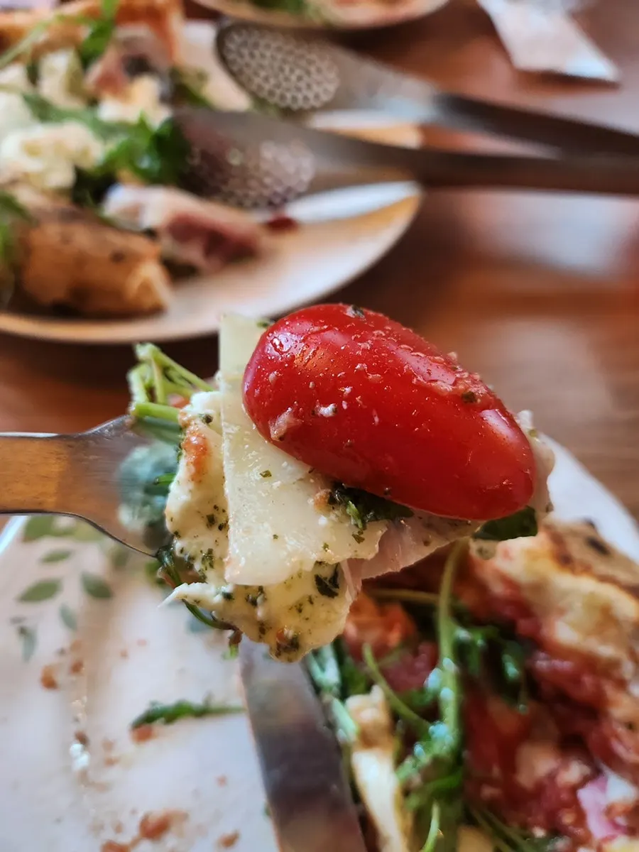 Toppings on the arugula, jamón, and burrata pizza