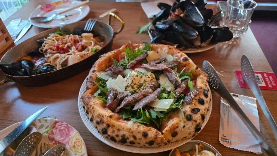 Table setting with steak pizza and shrimp tomato pasta