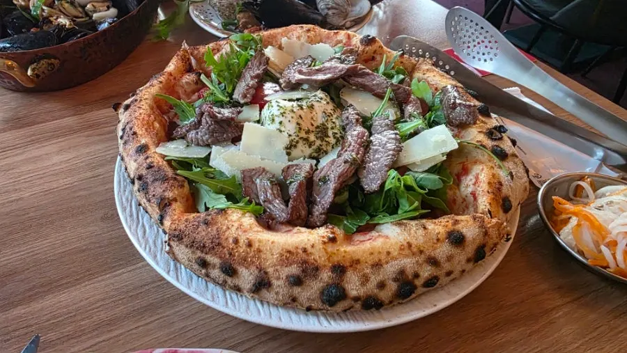 A whole wood-fired pizza topped with steak