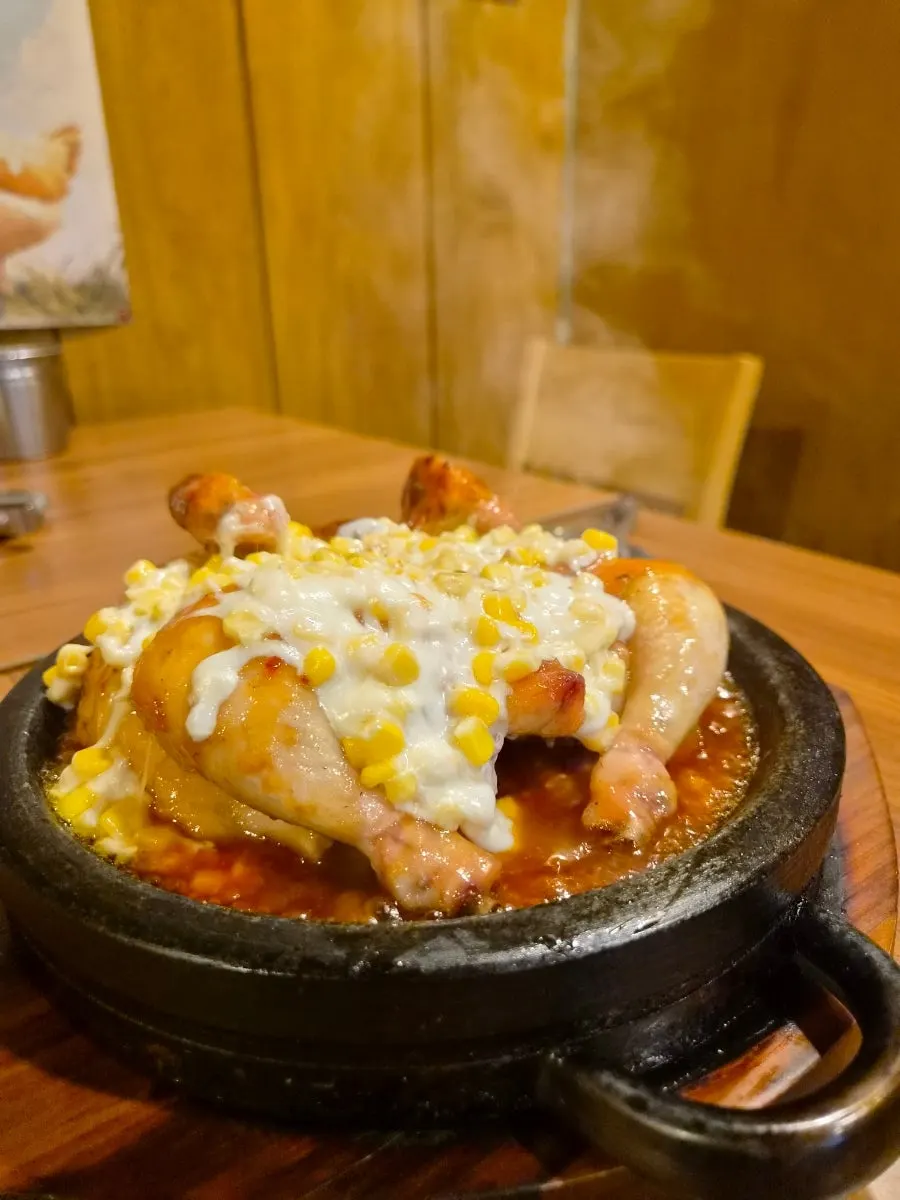 철판 위 콘치즈가 덮인 양념 장작구이 통닭