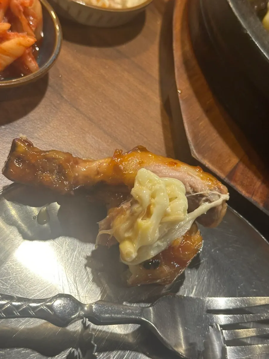 A large chicken leg picked up with tongs