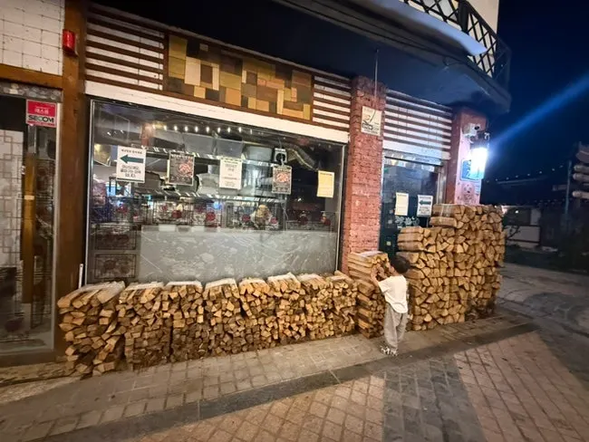 Oak firewood stacked in front of the restaurant