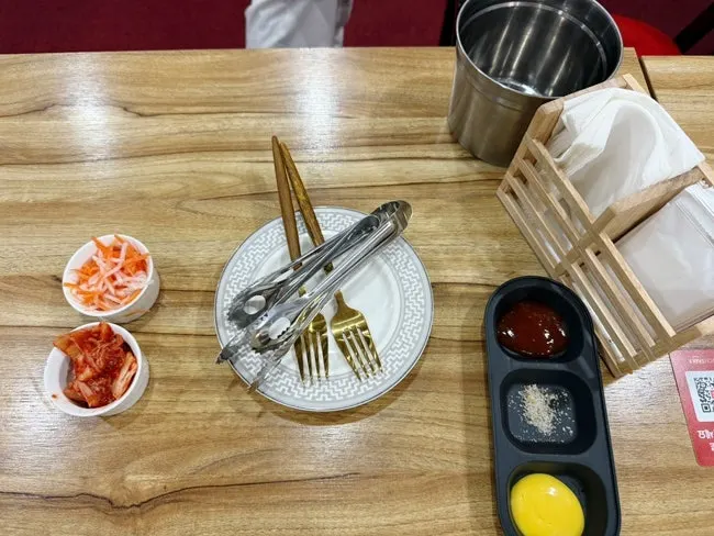 Basic table setting with salt, mustard, kimchi, and carrot-radish salad