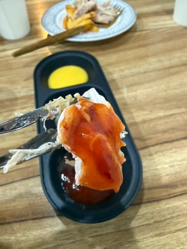 A piece of chicken held with chopsticks