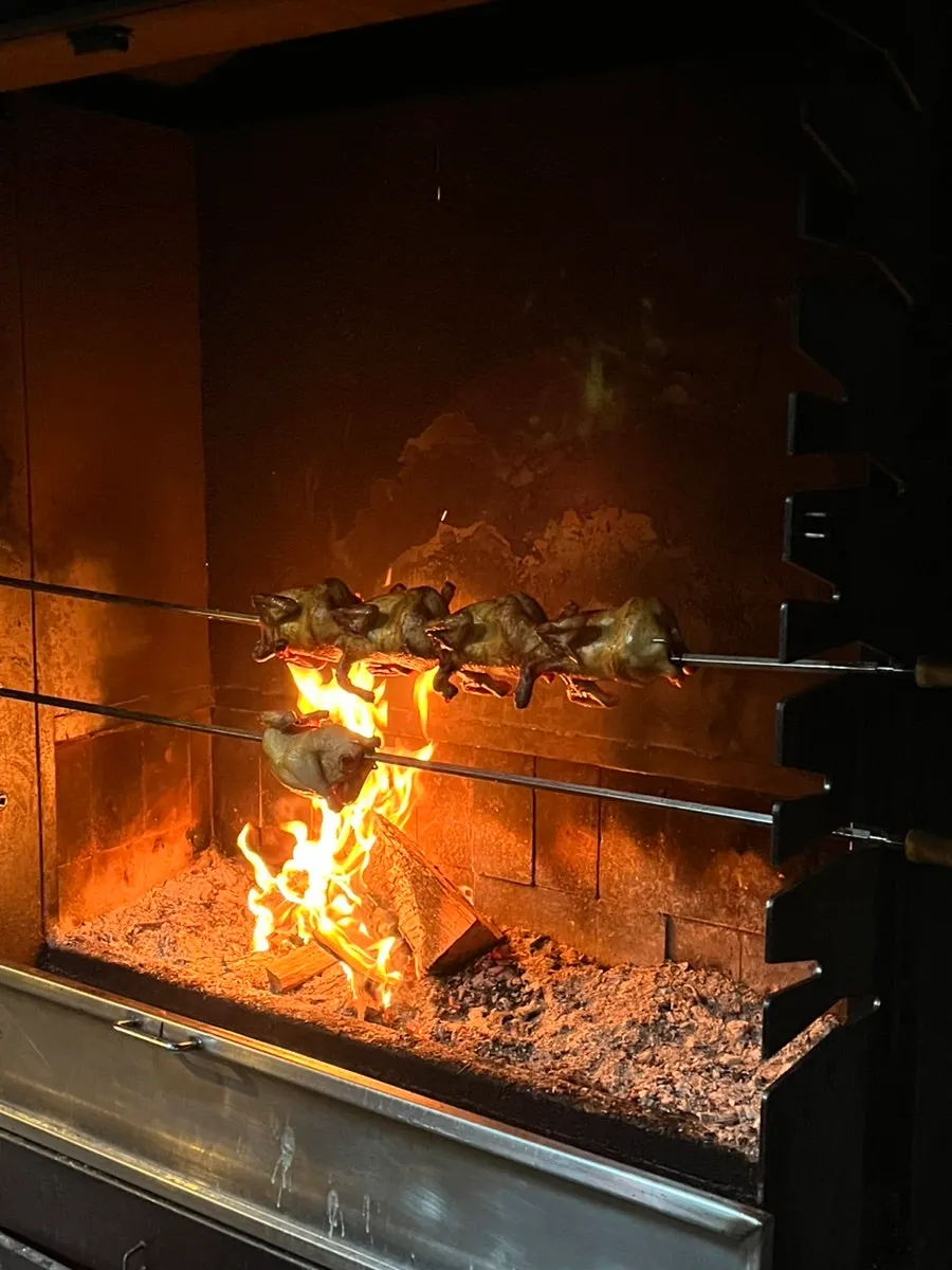 Chicken grilling over firewood at the back of the restaurant