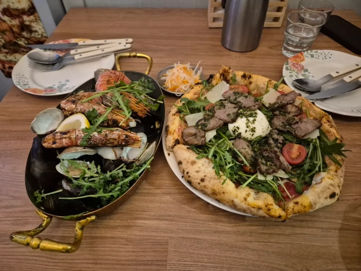 Steak burrata pizza and seafood pasta served on the table