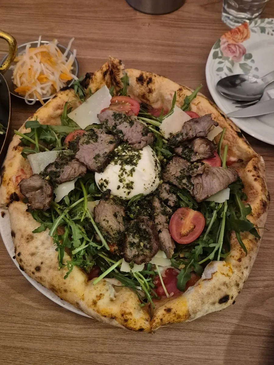 Wood-fired steak pizza topped with burrata cheese