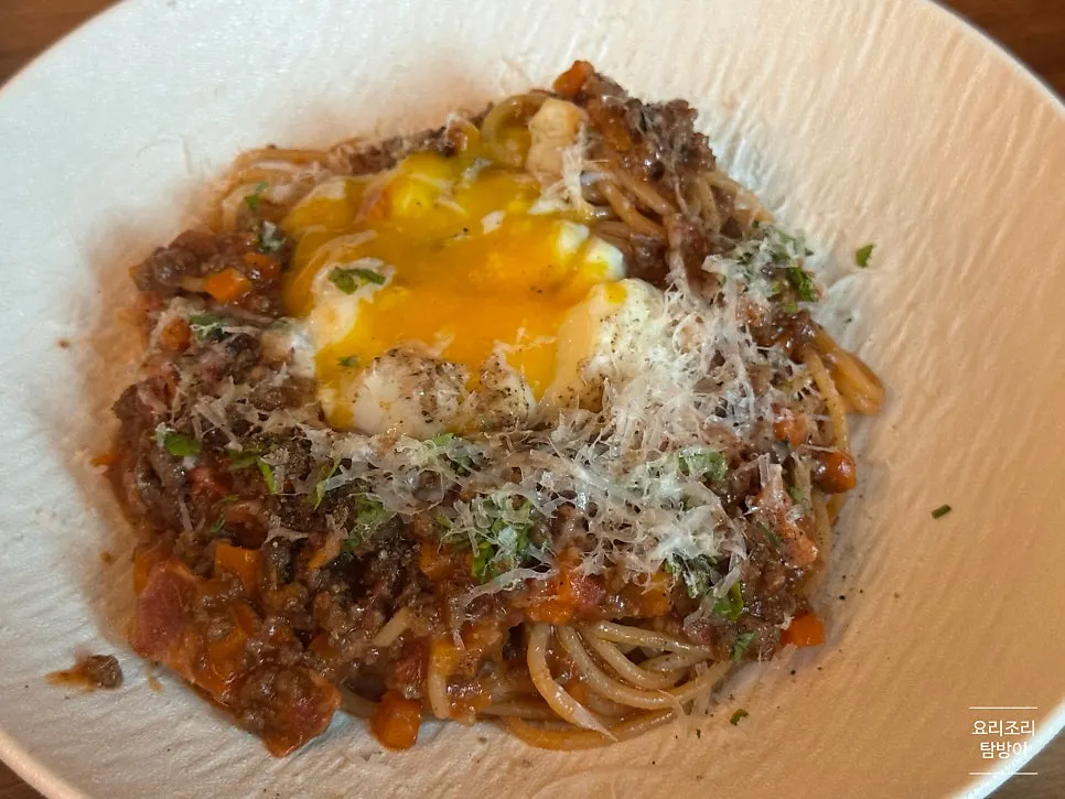 Fresh pasta mixed with broken poached egg and ragu sauce