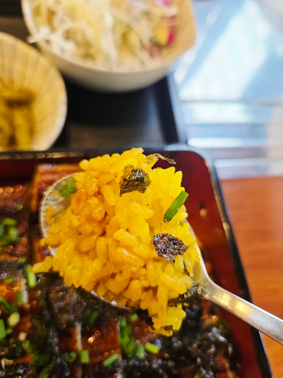 Vertical photo of eating the eel rice bowl with a spoon
