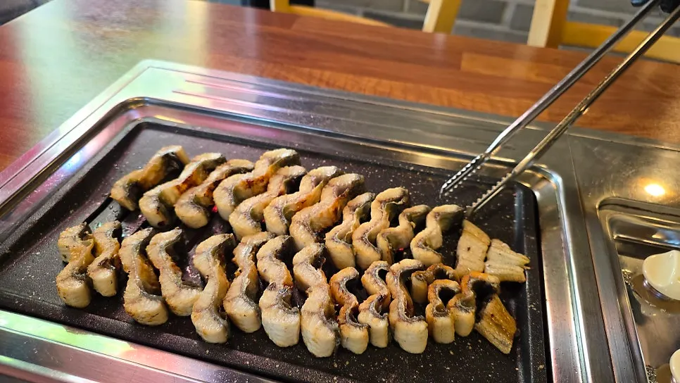 A piece of eel topped with ginger strips and sauce