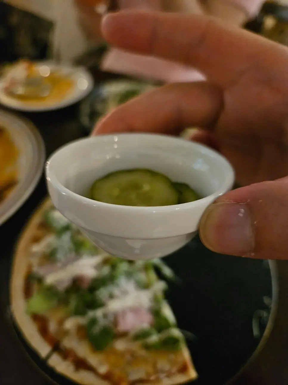A slice of thin pizza topped with arugula and ham