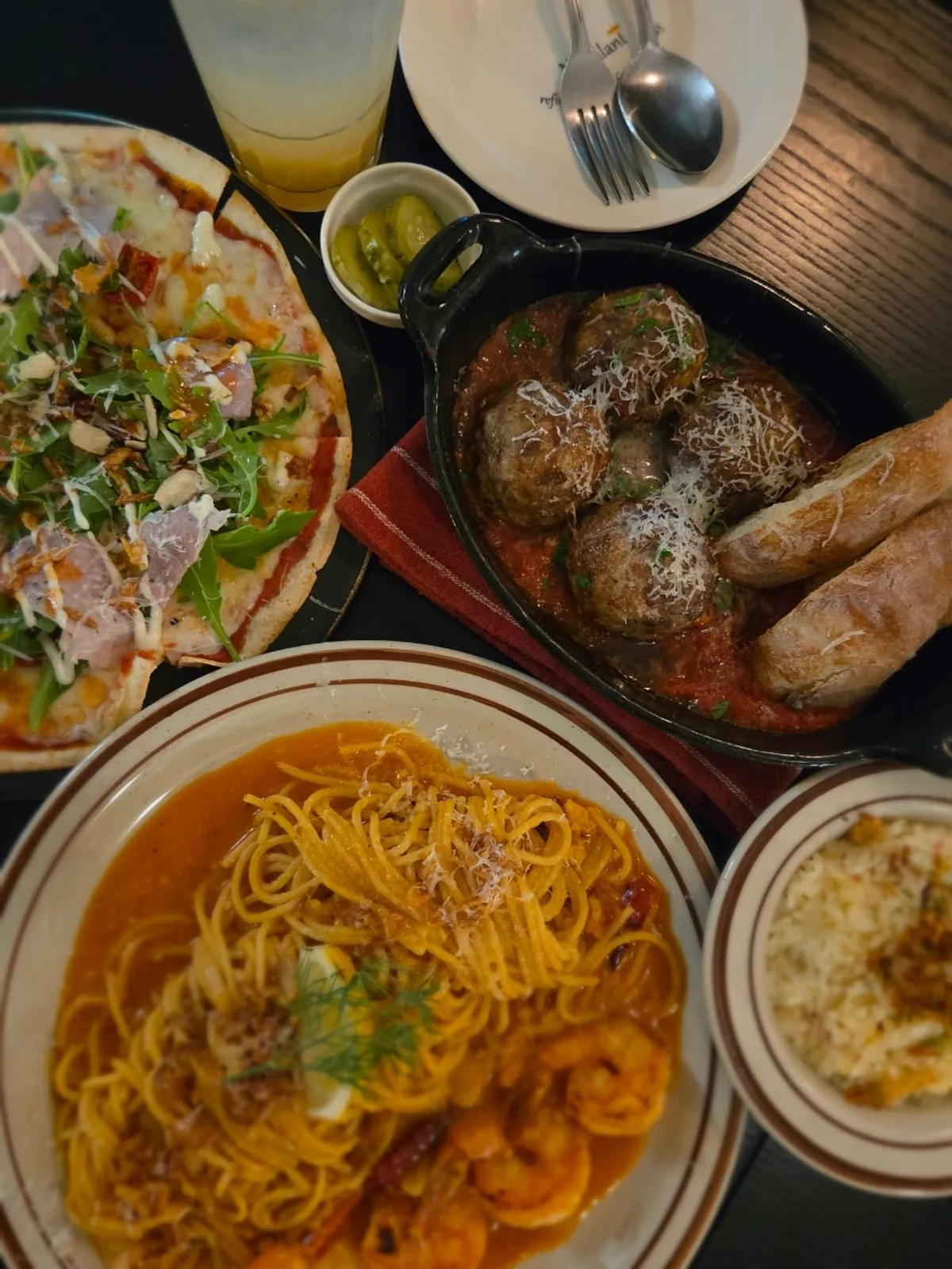 Table with meatballs, pasta, and thin pizza all together