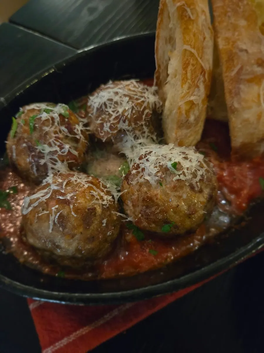 Dipping French baguette into meatball sauce