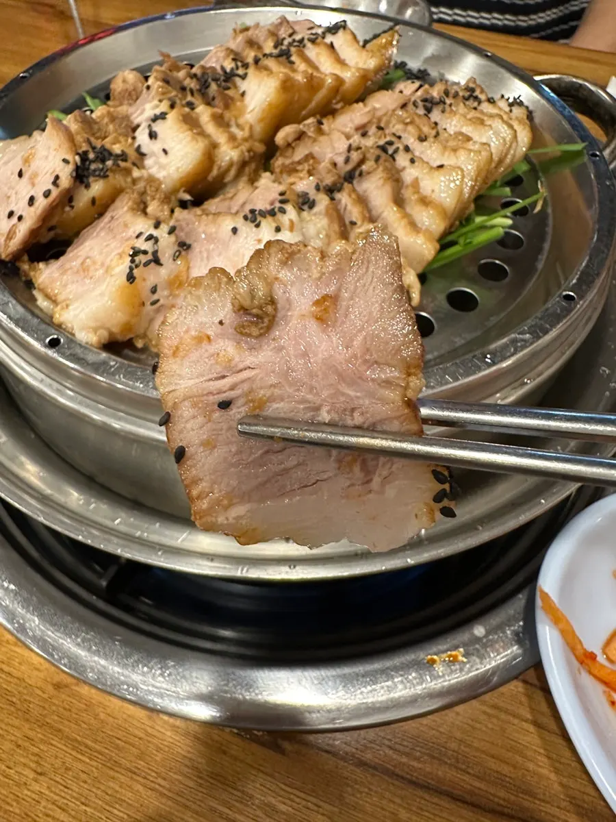 윤기 도는 수육 한 점을 집어 든 모습