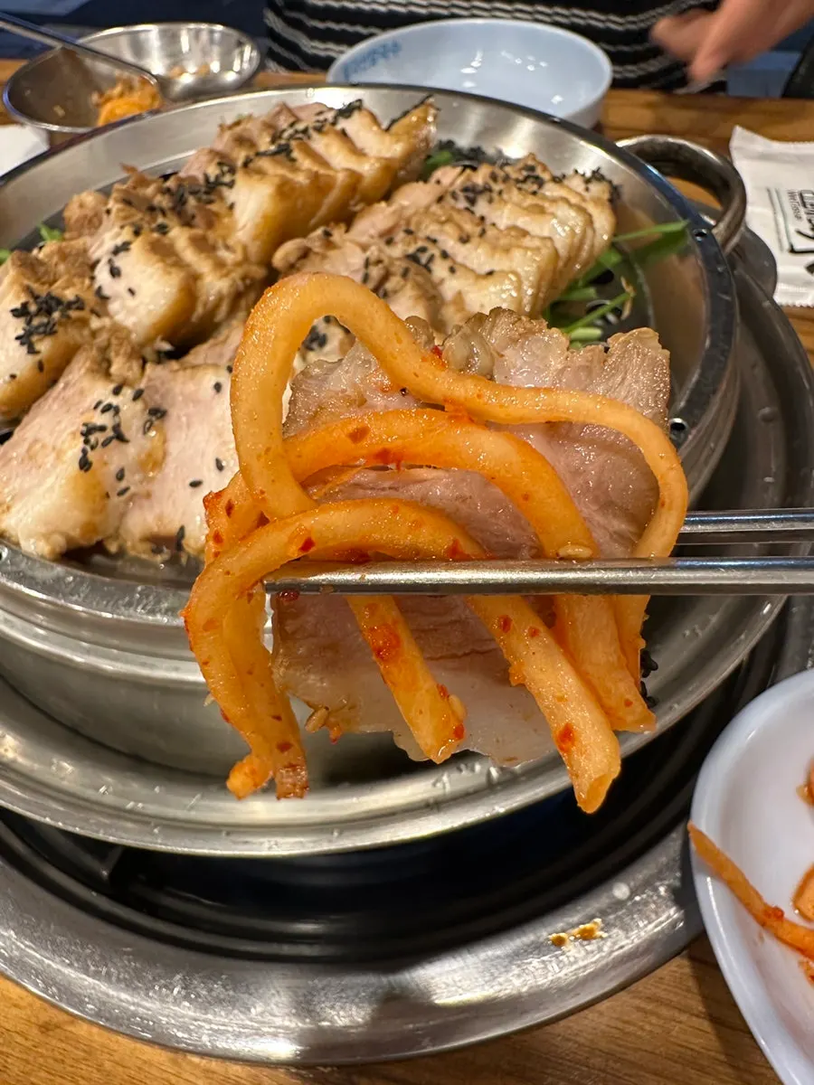 보쌈김치를 곁들인 수육 한 점