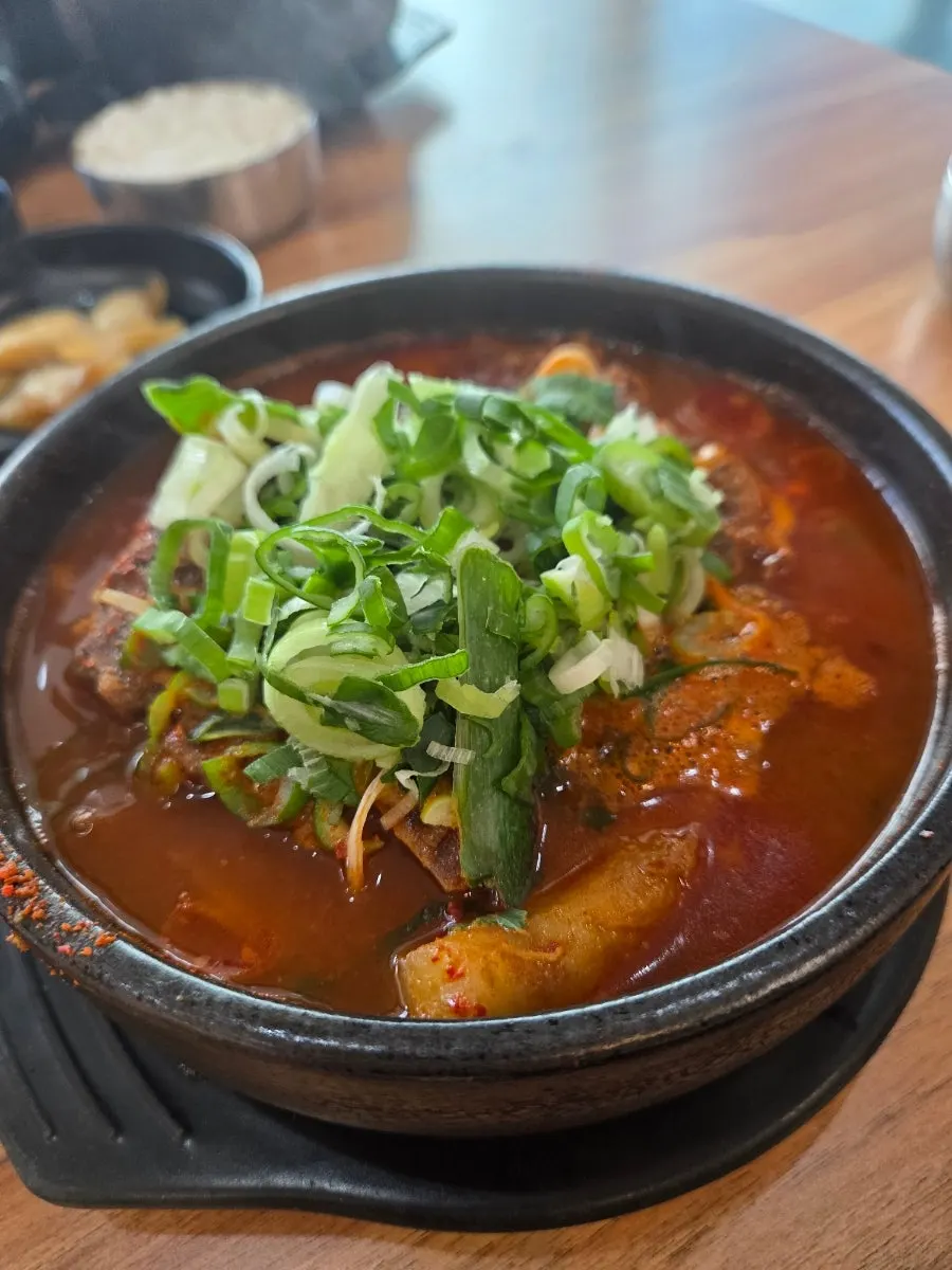 Spoonful of spicy broth being lifted from the pot
