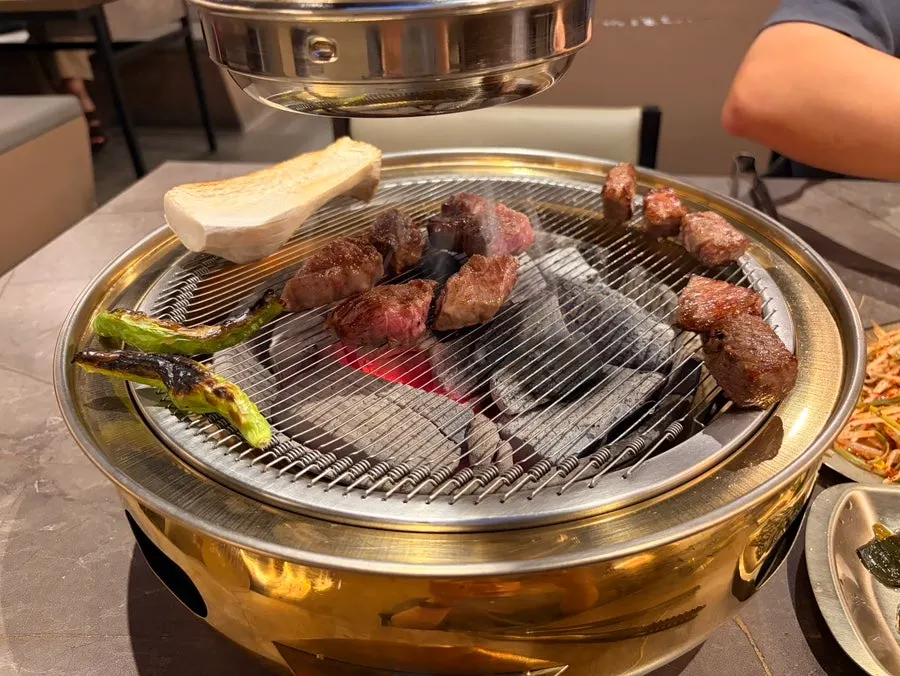 A piece of hanwoo dipped in salt and wasabi with myeongi namul