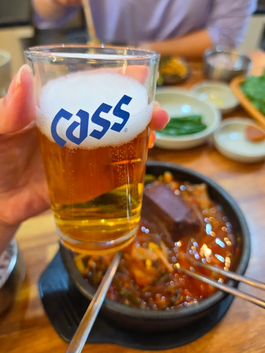 A glass of beer poured alongside the haejangguk