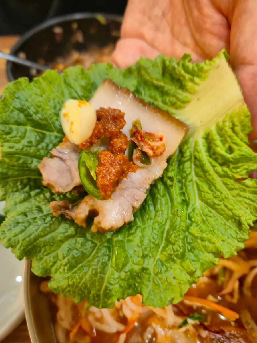 A piece of dombe pork wrapped in lettuce