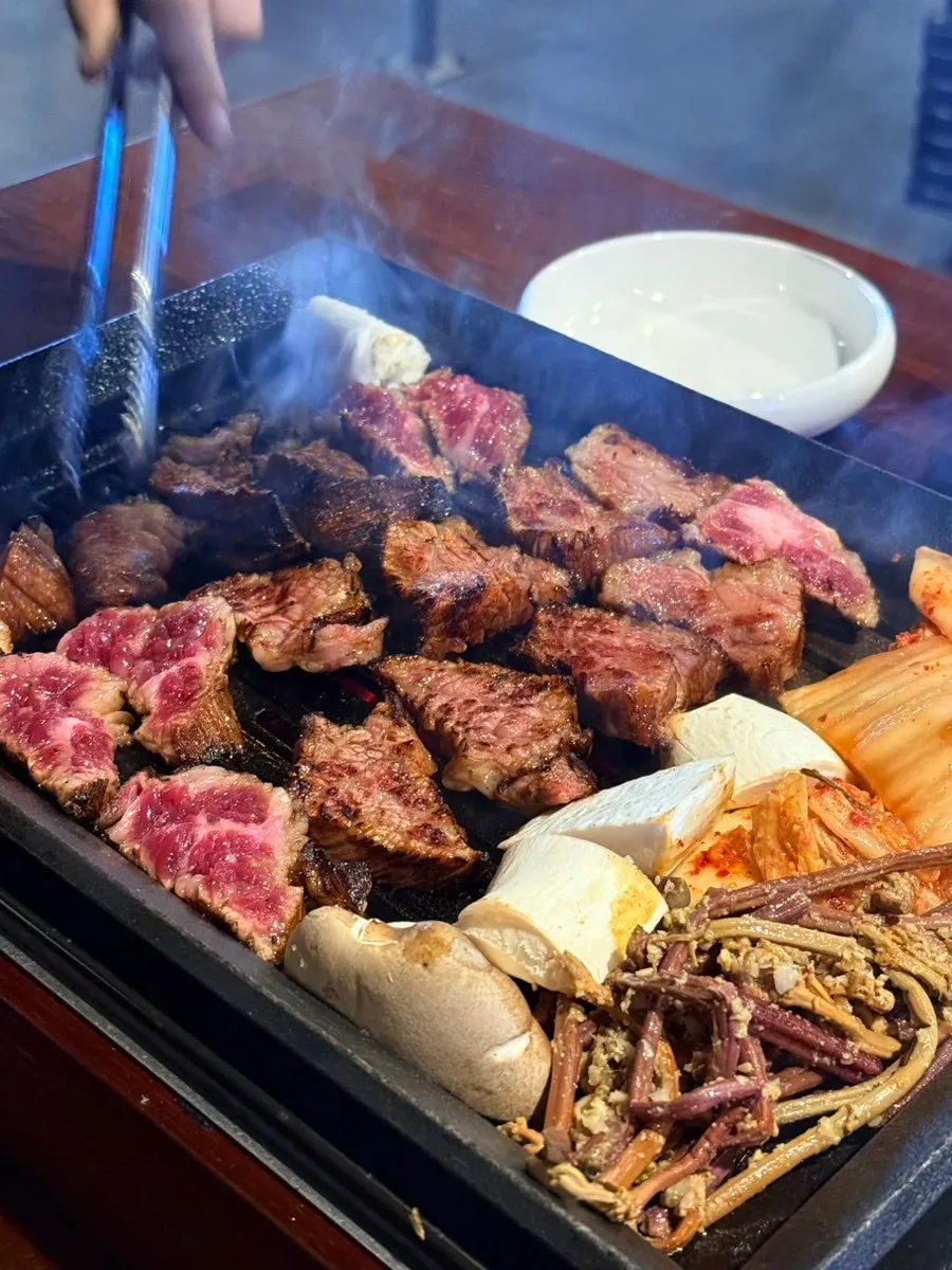 Staff member grilling marinated udaegalbi