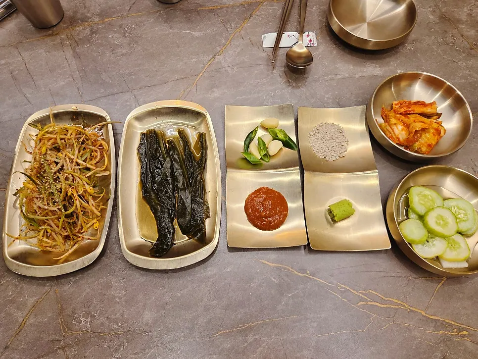 Table setting with coarse roasted salt, kimchi, cucumber, and other banchan