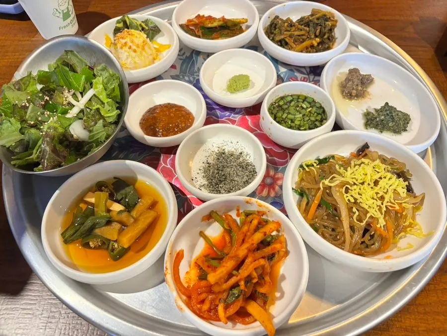 Side dish spread with salad, kimchi, and japchae at Jipbul Taebaek