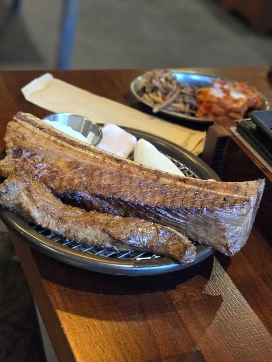 Beef ribs being seared over rice straw and charcoal