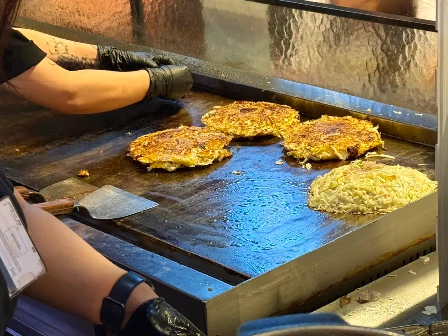 Yakisoba and okonomiyaki cooking on the iron griddle