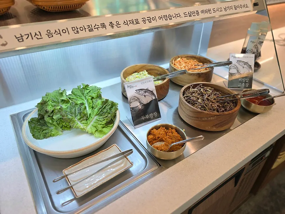 Self-serve corner with Korean side dishes, wrap vegetables, and namul