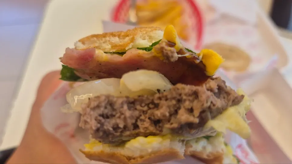 Burger with thick patty and onions alongside fries